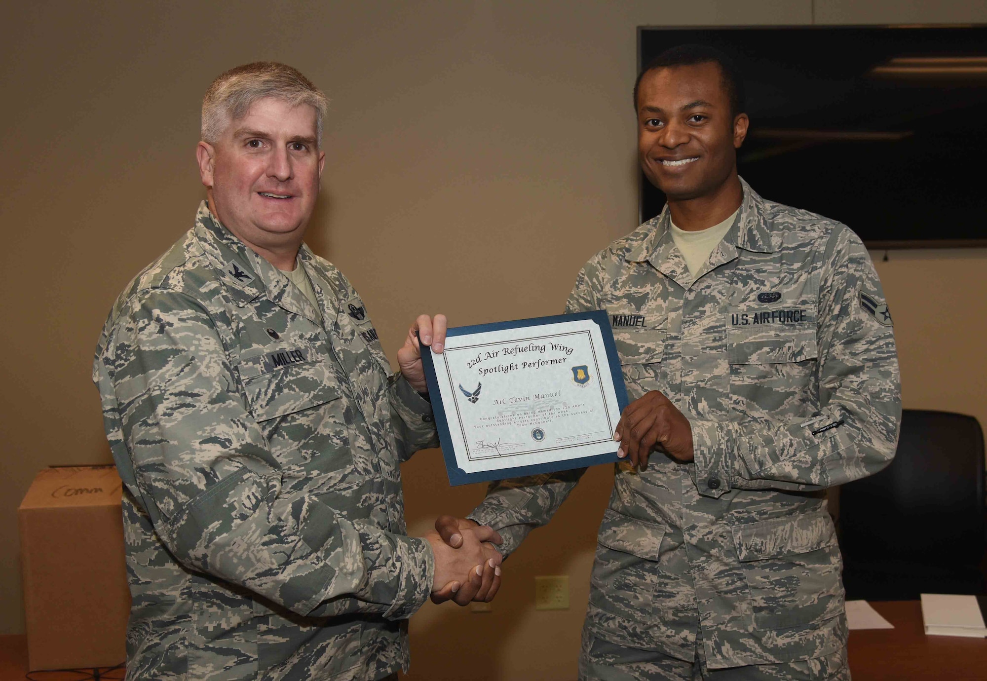 Airman 1st Class Tevin Manuel, 22nd Communications Squadron cyber surety technician, receives a certificate from Col. Albert Miller, 22nd Air Refueling Wing commander, May 18, 2017, at McConnell Air Force Base, Kan. Manuel earned the spotlight performer for the week of April 24-28. (U.S. Air Force photo/Airman 1st Class Erin McClellan)