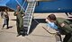 Maj. Jonathan Lauer, prepared to get wet, looks over at his son just before getting drenched with water May 22, 2017, Scott Air Force Base, Illinois. Tradition for a fini flight is getting hosed down by friends and family.  (U.S. Air Force photo by Christopher Parr)