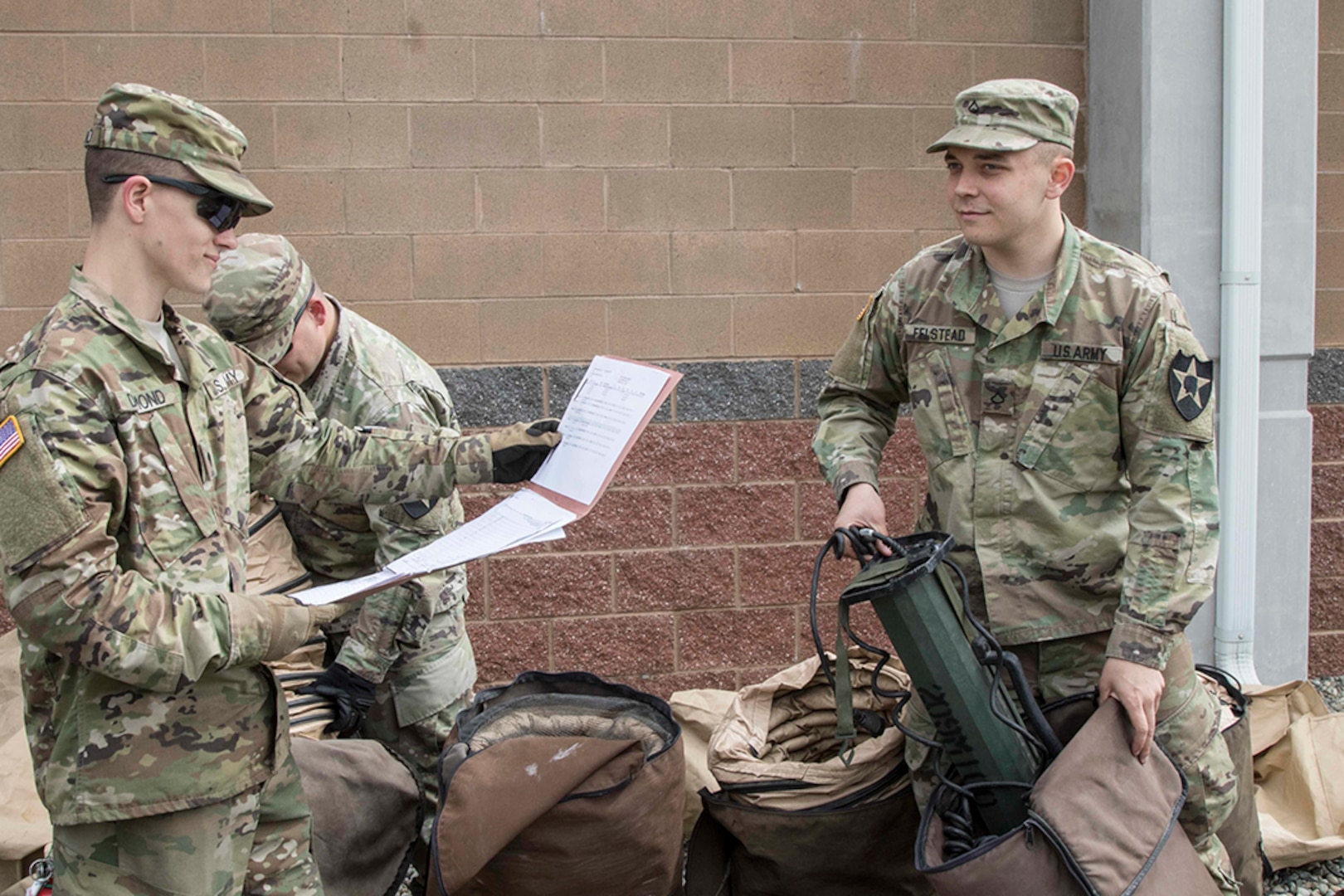 Spc. Aaron Dumond (left), a team leader with D Company, 23rd Brigade Engineer Battalion, 1-2 Stryker Brigade Combat Team, reads off a list of required items needed for turning in their Deployable Rapid Assembly Shelter.