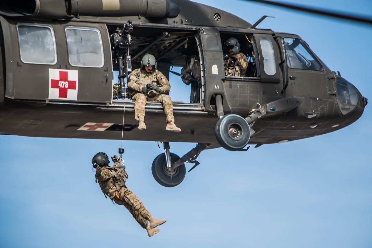 Nebraska Army National Guard Spc. Alec Rockford hoists down Chief Warrant Officer 3 David Flores while Sgt. Lawrence Lind takes photos from the crew chief seat during a training exercise, Dec. 26, 2016. The soldiers were deployed with Company G, 2-104th General Support Aviation Battalion in Afghanistan. Nebraska National Guard photo by Sgt. Charles Wilkins