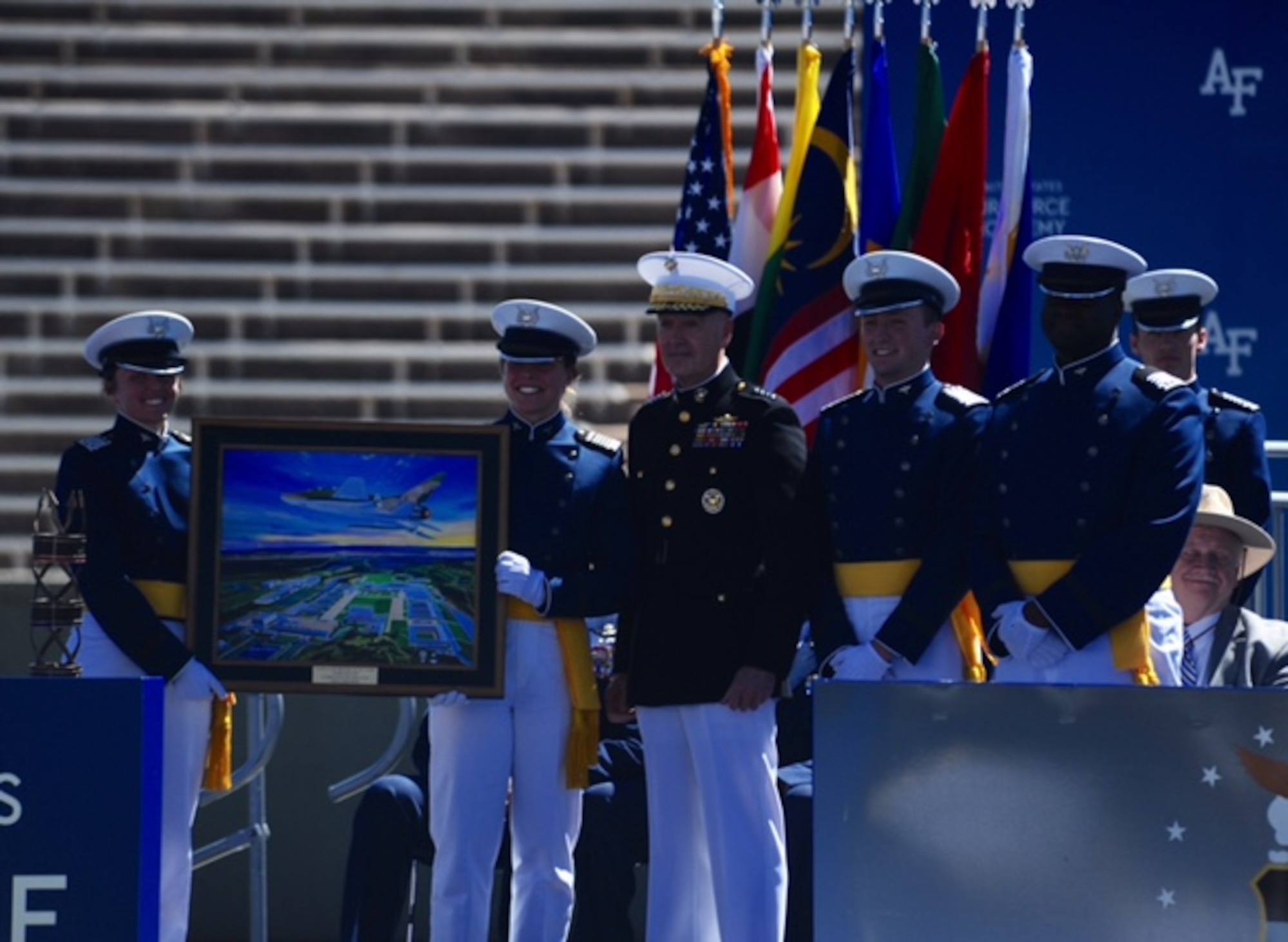 Chairman of the the Joint Chiefs of Staff Marine Gen. Joseph Dunford (center) stands between newly-minted second lieutenants after giving the commencement speech for the U.S. Air Force Academy's graduating Class of 2017. The new Air Force officers (left) hold a painting presented to the chairman by the Class of 2017. (U.S. Air Force photo/Tech. Sgt. Julius Delos Reyes)