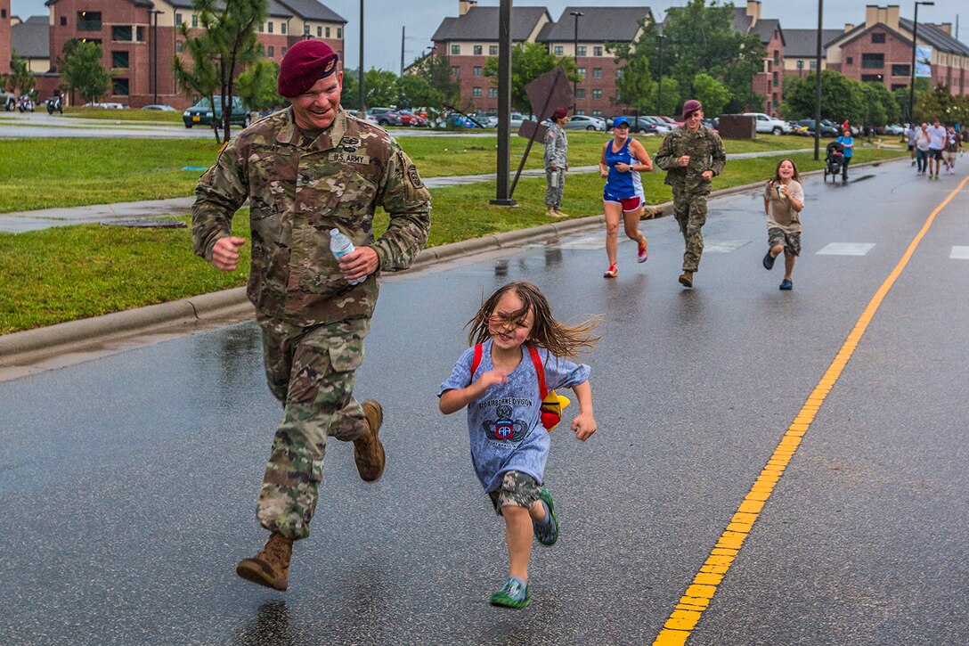 A paratrooper runs with a child during a family fun run as part of All American Week at Fort Bragg, N.C., May 23, 2017. The week celebrates the 82nd Airborne Division with events for soldiers, veterans and families. Army photo by Spc. L'Erin Wynn
