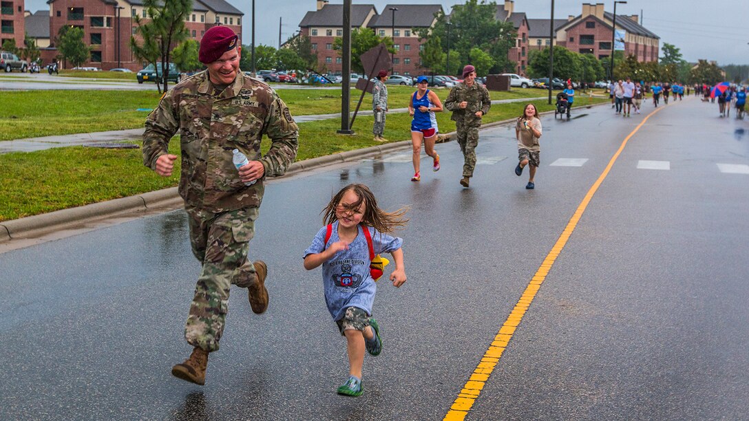 A paratrooper runs with a child during a family fun run as part of All American Week at Fort Bragg, N.C., May 23, 2017. The week celebrates the 82nd Airborne Division with events for soldiers, veterans and families. Army photo by Spc. L'Erin Wynn
