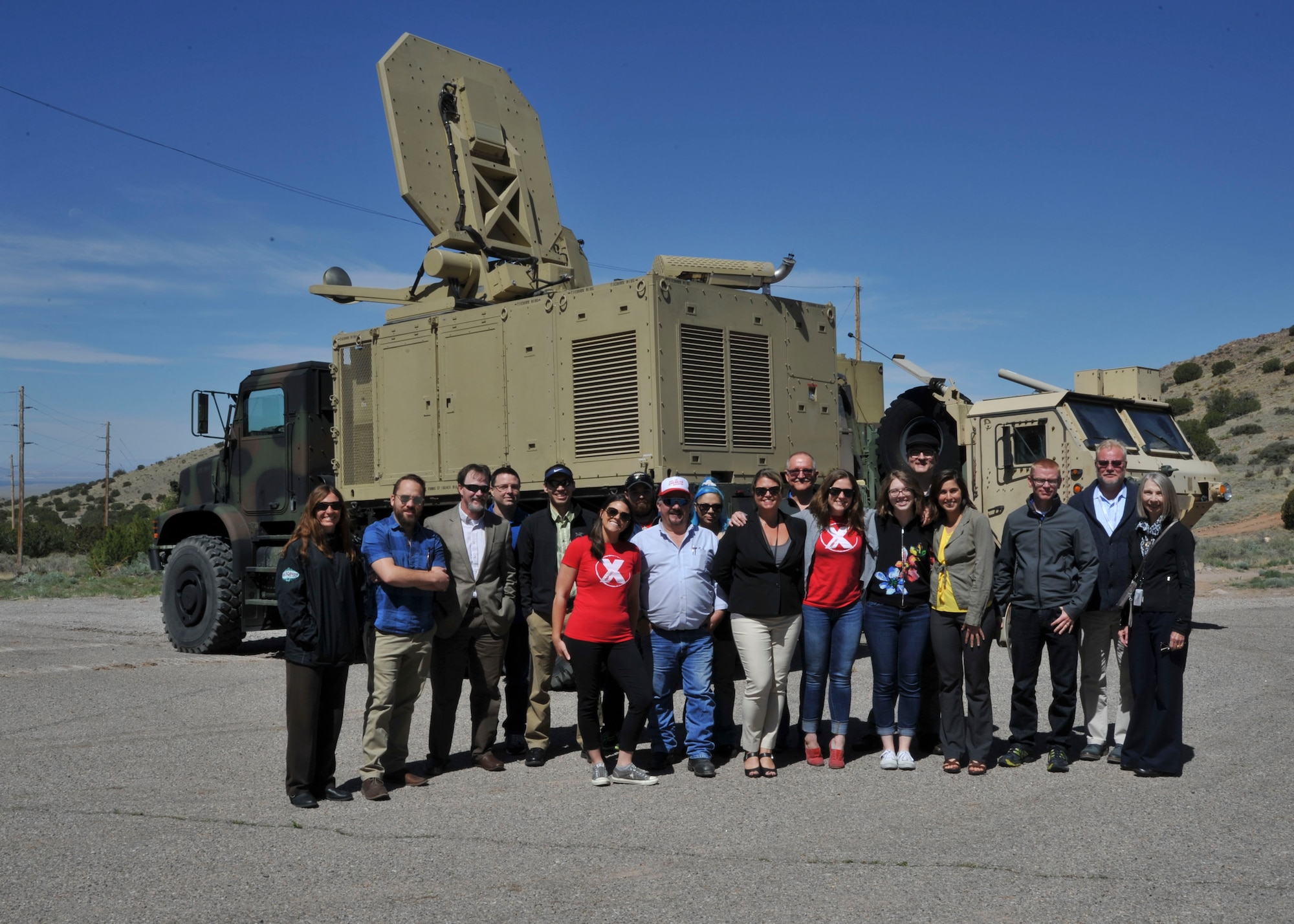 Local community members along with TEDX ABQ members take a photo in front of an active denial truck at Kirtland Air Force Base, New Mexico, May 17. Visitors spent the day learning about high power electromagnetics division technology which is often misrepresented via myth or social media. 