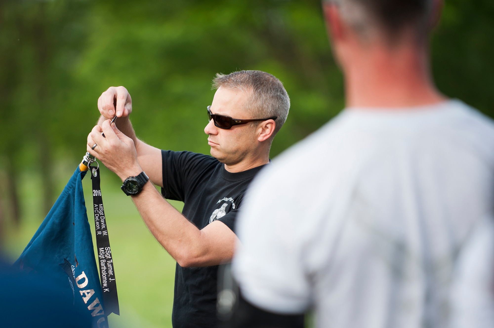 Tech. Sgt. Tim Brady, Air Mobility Command transportation systems and data management functional, adds a streamer with names of fallen aerial porters to a guidon during the 2017 Port Dawg Memorial Run at Scott Air Force Base, Ill., May 22, 2017. The run is an annual event to honor fallen aerial porters. (U.S. Air Force photo by Staff Sgt. Clayton Lenhardt)