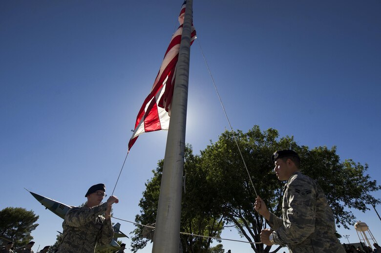 Airmen from the 99th Security Forces lower the American flag as the National Anthem plays during a ceremony for National Police Week at Nellis Air Force Base, Nev., May 19, 2017. National Police Week was created in 1962 by President John F. Kennedy to not only honor those who gave their lives in the line of duty, but also serve as a way to look back on the job they perform. (U.S. Air Force photo by Senior Airman Kevin Tanenbaum/Released)