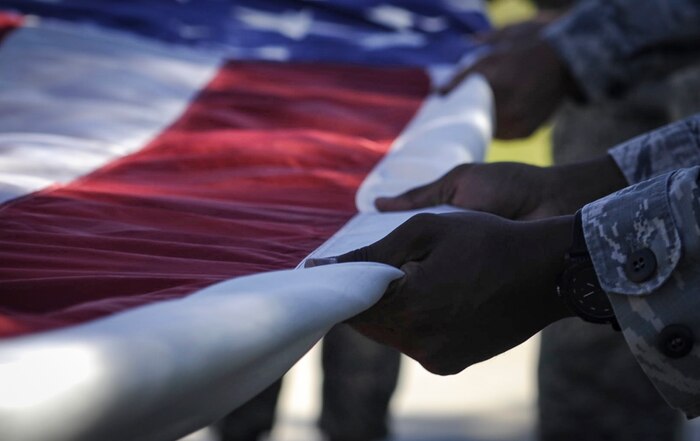 Airmen from the 99th Security Forces fold the American flag during a ceremony for National Police Week on Nellis Air Force Base, Nev., May 19, 2017. Police week at Nellis AFB was closed with a ceremony during reveille as SFS folded the flag and paid homage to those lost.  (U.S. Air Force photo by Senior Airman Kevin Tanenbaum/Released) 