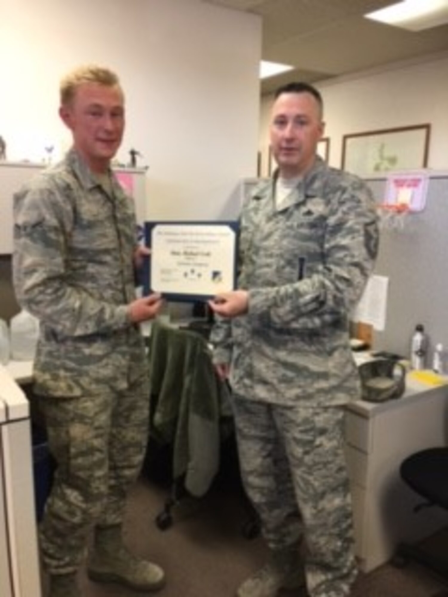 Airman Michael Scott, 49th Civil Engineer Squadron construction apprentice, is presented the Top III Airman award for April from Master Sgt. Timothy Gatten, 54th Aircraft Maintenance Squadron first sergeant and Top III President, at Holloman Air Force Base on May 24, 2017. During the month of April, Scott completed 13 surveys refining the base common installation picture and captured the placement of 1,200 feet of underground electrical conduit in direct support of a $2.4 million electrical distribution repair project.  (Courtesy photo)