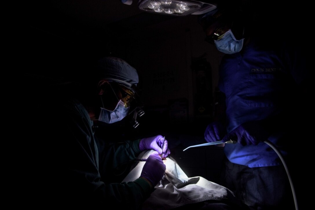 Navy Capt. Jaime Quejada, left, dental officer of the aircraft carrier USS Ronald Reagan; and Navy Petty Officer 3rd Class Davondrion Compton, right, a hospital corpsman from Bunkie, La., perform the first oral-laser surgery aboard the ship, May 22, 2017. Quejada performed an oral frenectomy on Navy Petty Officer 3rd Class Steven Wright, from Newark, N.J. Navy photo by Petty Officer 2nd Class Nathan Burke