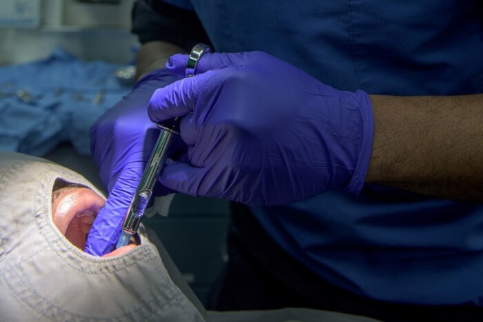 Hospital Corpsman 3rd Class Davondrion Compton, a surgical technician, injects Boatswain's Mate 3rd Class Steven Wright with local anesthetic aboard the aircraft carrier USS Ronald Reagan. Compton was preparing Wright for an oral frenectomy, which was the first oral-laser surgery performed aboard a forward-deployed aircraft carrier. Navy photo by Mass Communication Specialist 2nd Class Nathan Burke