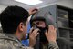 Senior Airman Carlos Garza, 80th Operations Support Squadron aircrew flight equipment technician, adjusts the helmet and mask of a student pilot to check proper fit and seal. A set of pilot equipment consists of a helmet, mask, parachute and G-suit, more than 140 sets are inspected weekly. (U.S. Air Force photo by Senior Airman Robert L. McIlrath)