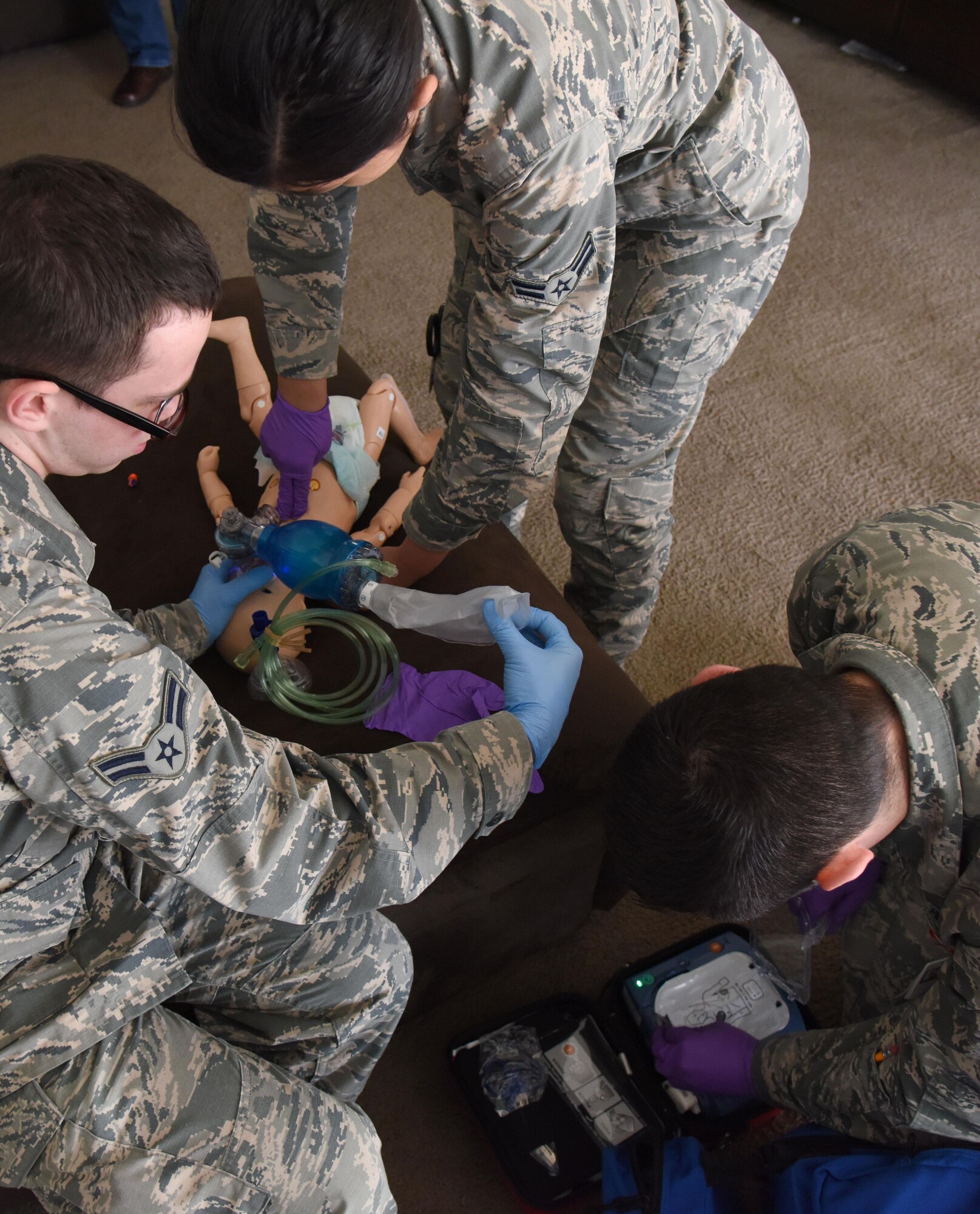 Airmen 1st Class Andrew Frost and Jacqueline Salazar, 81st Medical Operations Squadron medical technicians, and Senior Airman Brock Mauldin, 81st MDOS medical technician, treat an infant “patient” found unresponsive in East Falcon subdivision May 24, 2017, in Biloxi, Miss., as part of a medical emergency scenario. Emergency room staff members coordinated with the simulation lab to use human patient simulators for running various advanced cardiac life support scenarios to improve Keesler’s new medical technicians’ skills and get them familiar with emergency equipment. (U.S. Air Force photo by Kemberly Groue)