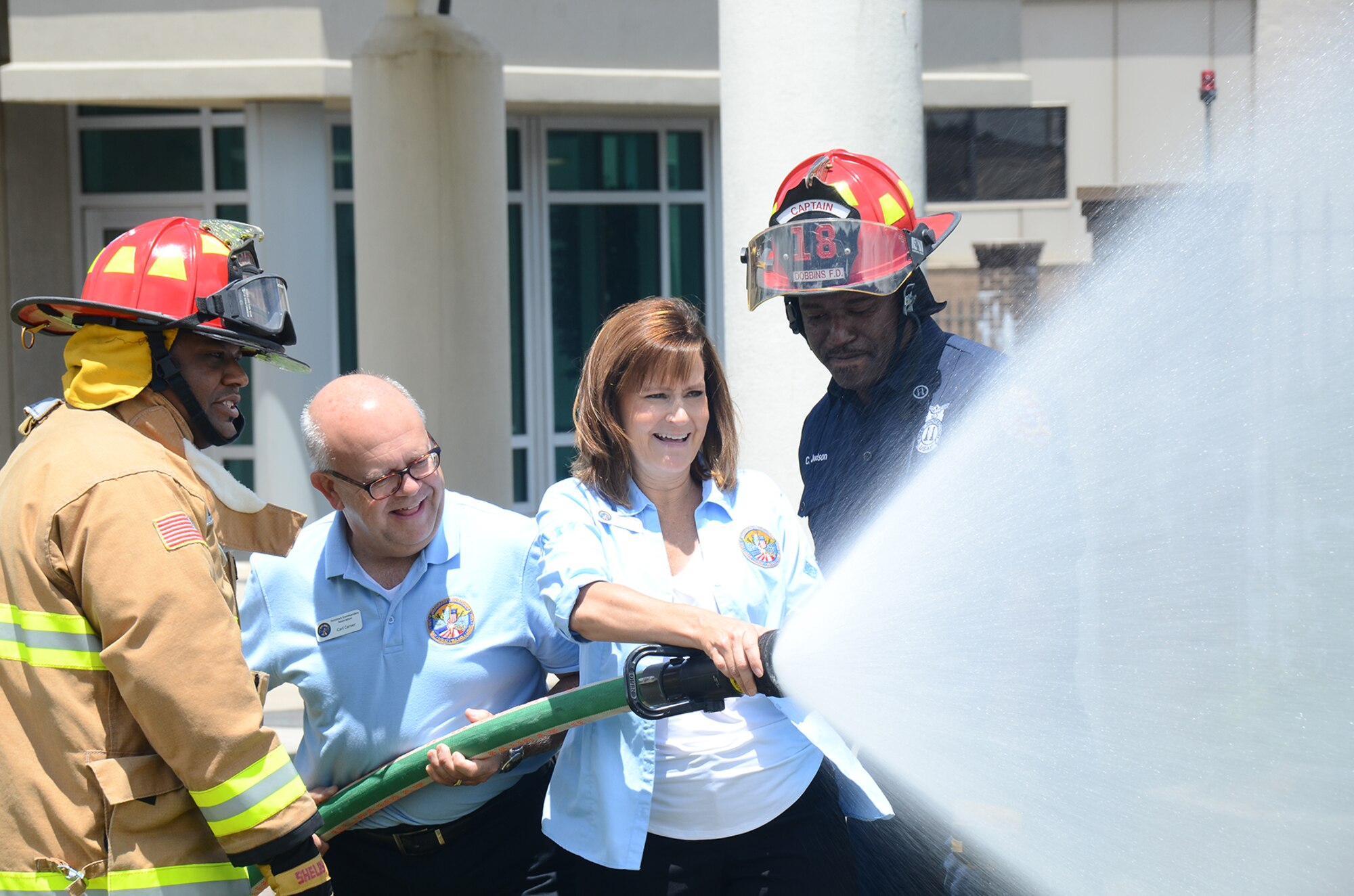 Rodney Long and Charles Judson of the Dobbins Fire Department give members of the Honorary Commanders Association Class of 2017 the opportunity to operate a fire hose during their annual "Dobbins Day" May 25, 2017 at Dobbins Air Reserve Base, Georgia. The HCA annually selects community and business leaders and pairs them with military commanders in a yearlong program, giving the leaders the opportunity to learn more about local military activities, their impact on our economy and various aspects of the national defense system. (U.S. Air Force photo/Don Peek)