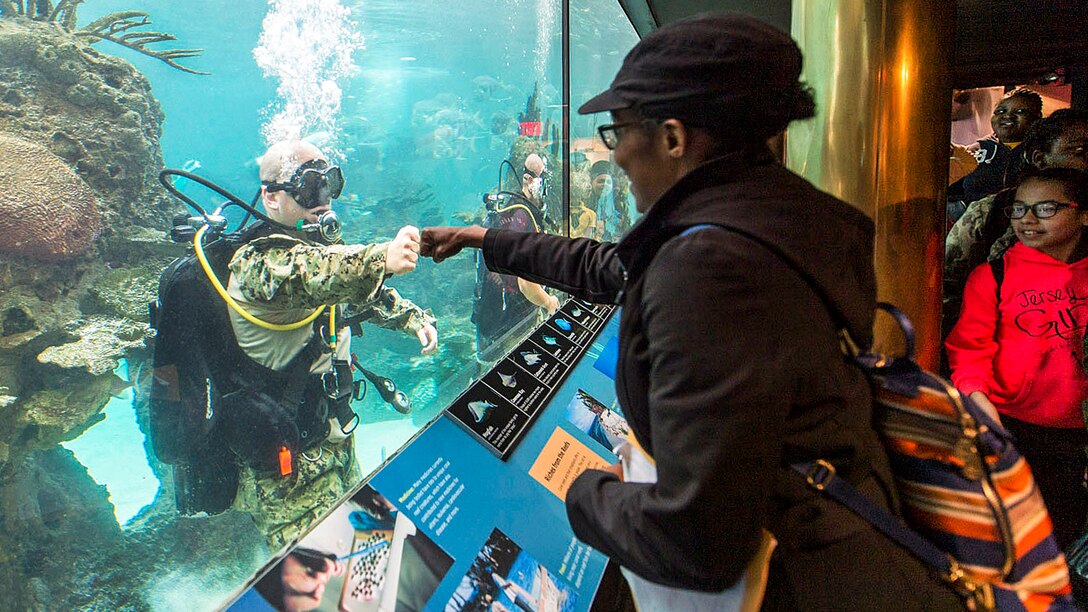 Navy Petty Officer 1st Class Sean Dargie fist bumps a visitor at the New York Aquarium during the 29th annual Fleet Week New York, May 24, 2017. The event provides an opportunity for residents of New York and the surrounding area to meet sailors, Marines and Coast Guardsmen. Dargie is assigned to assigned to Mobile Diving and Salvage Unit 2. Navy photo by Petty Officer 2nd Class Charles Oki