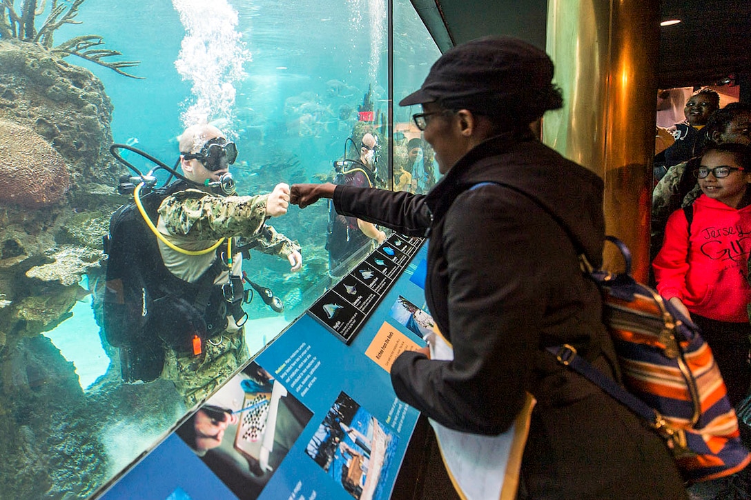 Navy Petty Officer 1st Class Sean Dargie fist bumps a visitor at the New York Aquarium during the 29th annual Fleet Week New York, May 24, 2017. The event provides an opportunity for residents of New York and the surrounding area to meet sailors, Marines and Coast Guardsmen. Dargie is assigned to assigned to Mobile Diving and Salvage Unit 2. Navy photo by Petty Officer 2nd Class Charles Oki