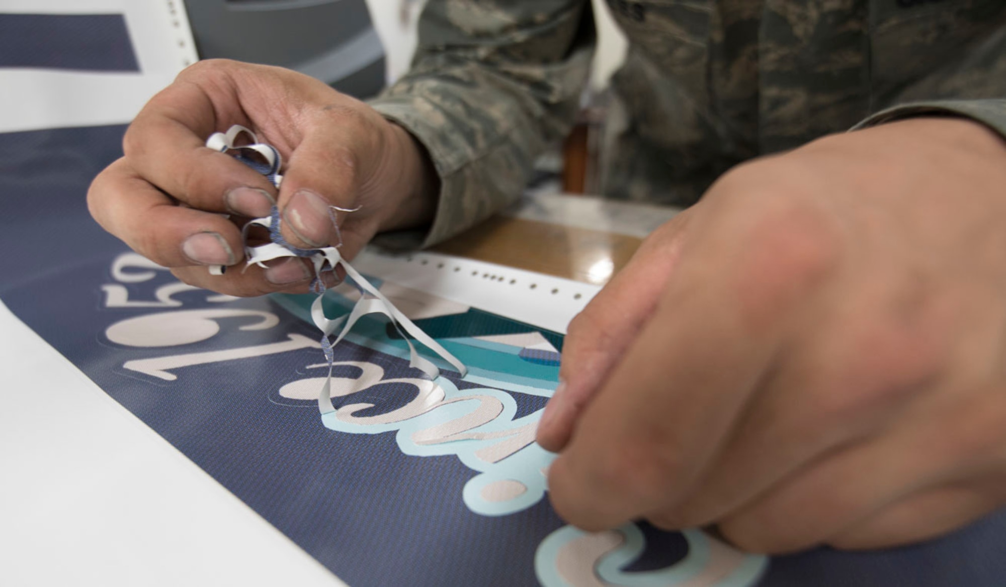Staff Sgt. Jared Boles, 374th Maintenance Squadron aircraft structural maintenance craftsman, delicately removes excess vinyl from a newly printed nose art piece for a C-130J Super Hercules at Yokota Air Base, Japan, May 19, 2017. The nose art is printed on vinyl by select members of the fabrication shop and carefully applied to the prepped surface of the aircraft. The digital approach took upwards of 30 hours to complete the project from sketch pad to prepress printing. (U.S. Air Force photo by Yasuo Osakabe)
