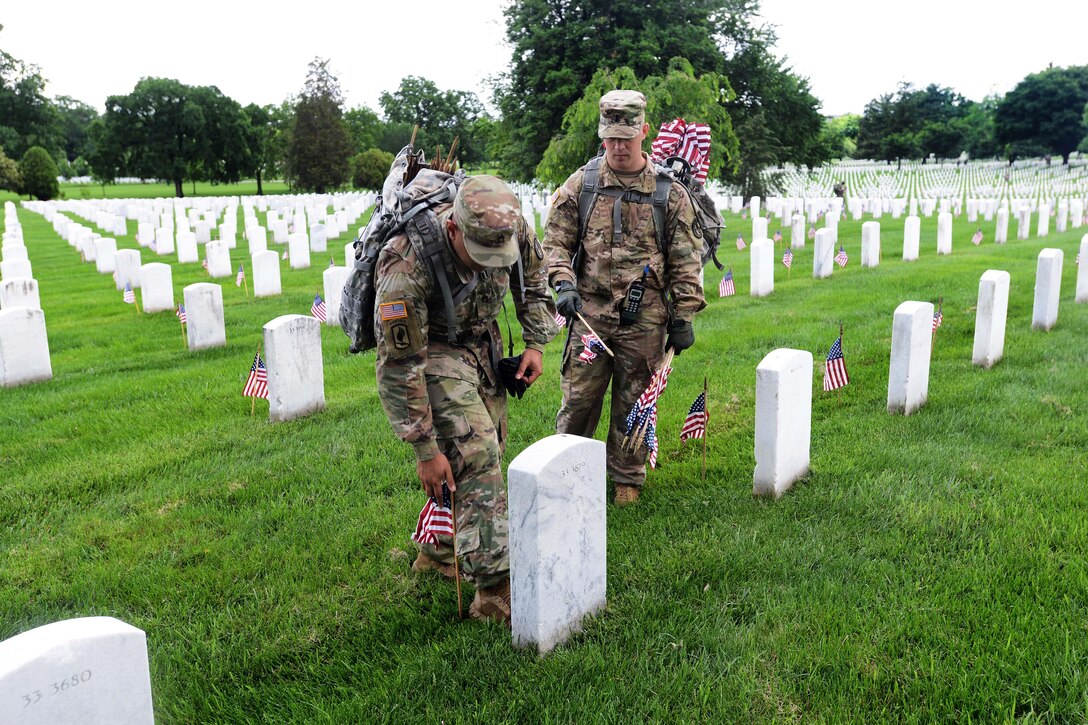 Army 1st Lt. Virgil Walker, right, looks on while Army Staff Sgt. David Rivera places an American flag in front of a headstone during "Flags In" at Arlington National Cemetery in Arlington, Va., May 25, 2017. Walker is a transportation platoon leader, and Rivera is a squad leader assigned to the 3rd U.S. Infantry Regiment, known as "The Old Guard.” DoD photo by Sebastian J. Sciotti Jr.                