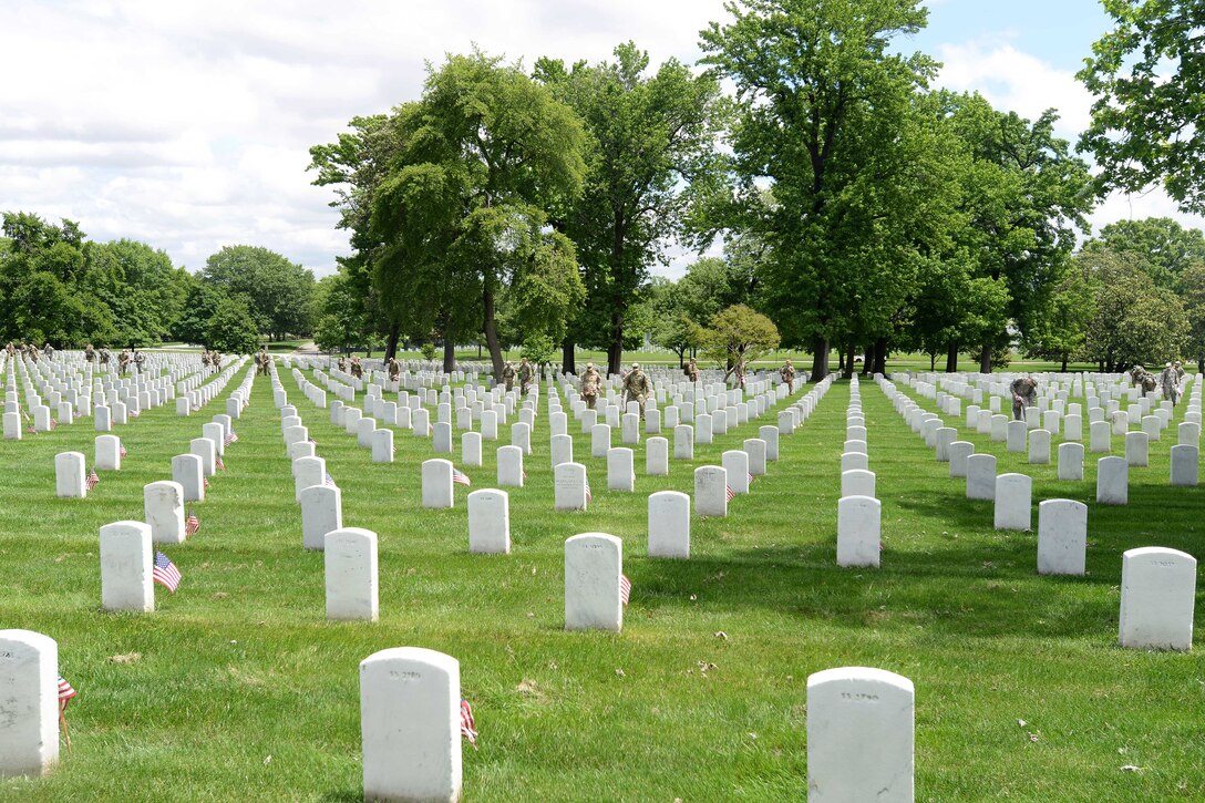 Soldiers place American flags in front of headstones during "Flags In" at Arlington National Cemetery in Arlington, Va., May 25, 2017. DoD photo by Sebastian J. Sciotti Jr.