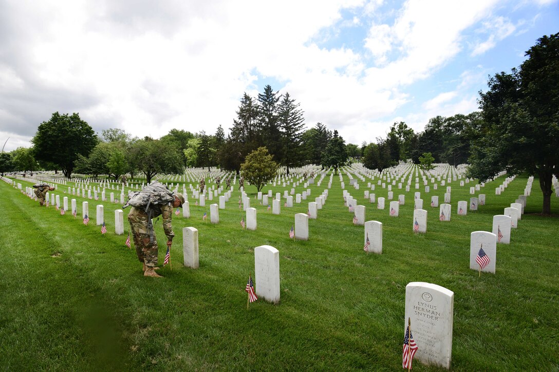 Army Spc. Josue Rivera places an American flag in front of a headstone during "Flags In" at Arlington National Cemetery in Arlington, Va., May 25, 2017. Rivera is a culinary arts specialist assigned to the 3rd U.S. Infantry Regiment, known as "The Old Guard." DoD photo by Sebastian J. Sciotti Jr.