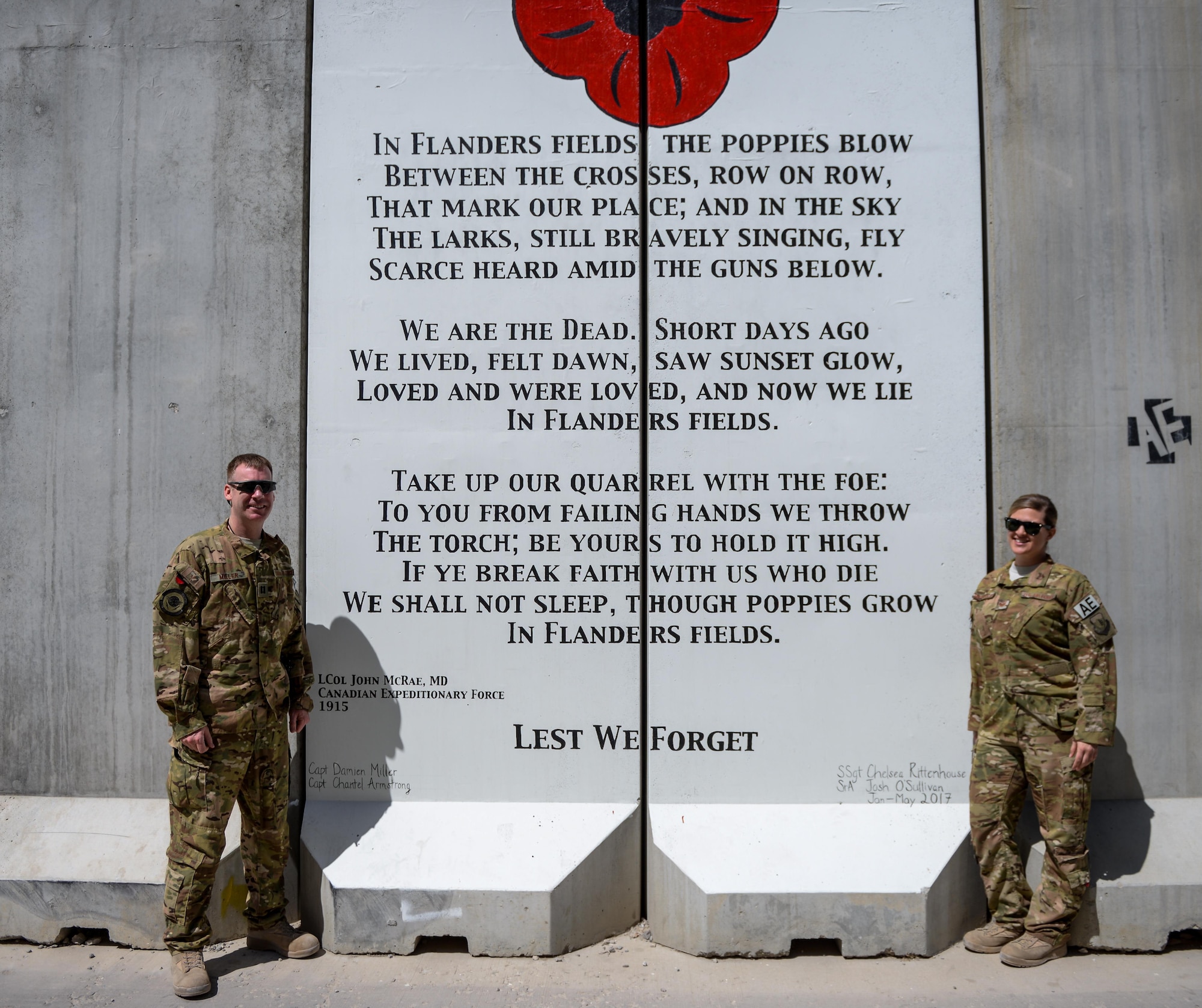 Royal Canadian Air Force Capt. Damien Miller and U.S Air Force Staff Sgt. Chelsea Rittenhouse, of the 455th Expeditionary Aeromedical Evacuation Squadron, stand in front of their artwork at Bagram Airfield, Afghanistan. The design, drafted by Miller, depicts a red poppy above the storied poem, "In Flanders Fields." The poem and poppy have become symbols of remembrance in Commonwealth nations. The poem was originally written by Canadian Expeditionary Force Lt. Col. John McCrae following the Second Battle of Ypres in World War I, 1915. (U.S. Air Force photo by Capt. Keenan Kunst)