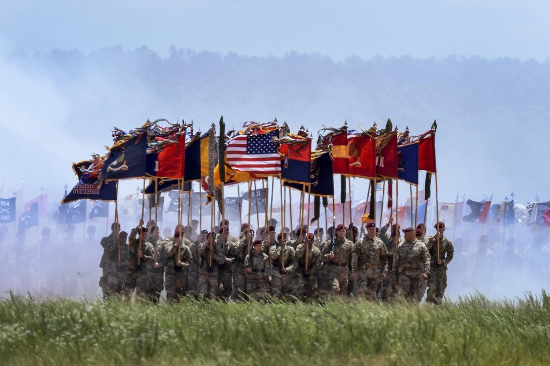 Soldiers carry flags as they march off Sicily drop zone during an airborne review at Fort Bragg, N.C., May 25, 2017. The review is the culminating event of 100th All American Week. The soldiers are assigned to the 82nd Airborne Division. Air Force photo by Senior Airman Ericka Engblom