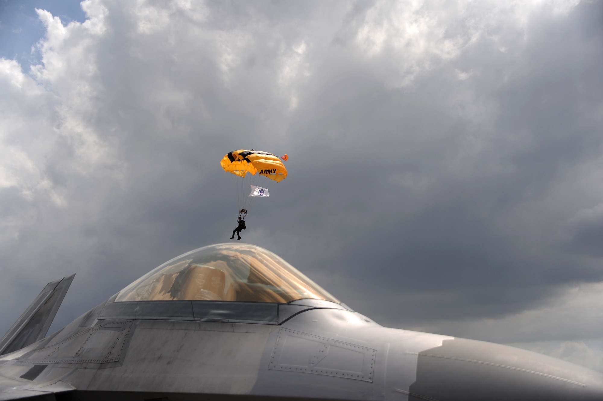 An Army Golden Knights Parachute Team member soars over an Air Force F-22 Raptor during the Memorial Day weekend National Salute to America’s Heroes Miami Air and Sea Show at U.S. Coast Guard Air Station Miami in Opa-Locka, Fla., May 26, 2017. Air Force, Army, Navy, Marine Corps, and Coast Guar service members are participating in the air and sea show to demonstrate their capabilities to the public, educate, and increase awareness of each branch’s unique mission and role. (U.S. Air Force photo by Senior Airman Erin Trower)