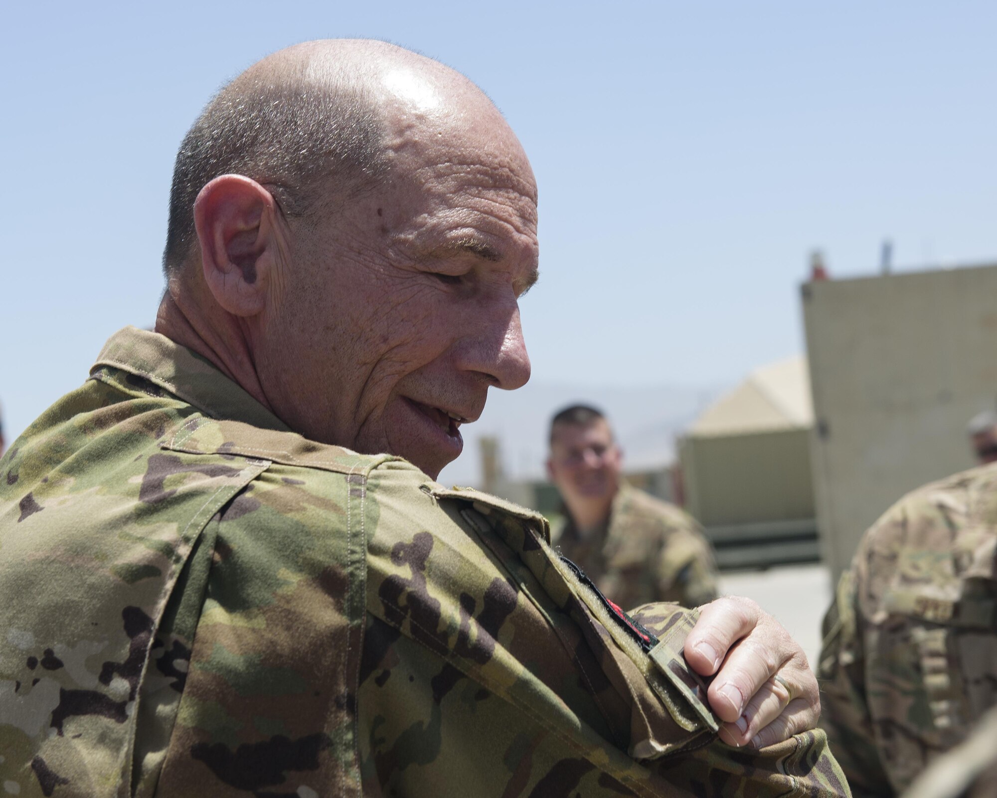 Gen. Mike Holmes, commander of Air Combat Command, places a patch on his Occupational Camouflage Pattern uniform at Bagram Airfield, Afghanistan, May 25, 2017. Holmes met with Bagram Airmen and Soldiers, who gave him their unit patches in appreciation, which he placed on his uniform. (U.S. Air Force photo by Staff Sgt. Benjamin Gonsier)