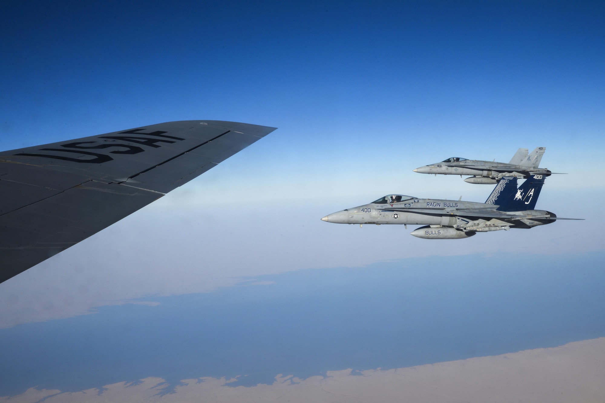 Two U.S. Navy F/A-18Cs from the Strike Fighter Squadron VFA-37 Ragin' Bulls fly in formation alongside a U.S. Air Force KC-135 Stratotanker during a combat refueling mission over Southwest Asia May 21, 2017.  KC-135 Stratotankers, from the 340th Expeditionary Air Refueling Squadron at Al Udeid Air Base, Qatar, maintain a 24/7 presence in the Area Of Responsibility, supporting U.S. and Coalition forces in the air and on the ground, contributing to Operation Inherent Resolve and the fight against ISIS. (U.S. Air National Guard photo by Master Sgt. Andrew J. Moseley/Released)