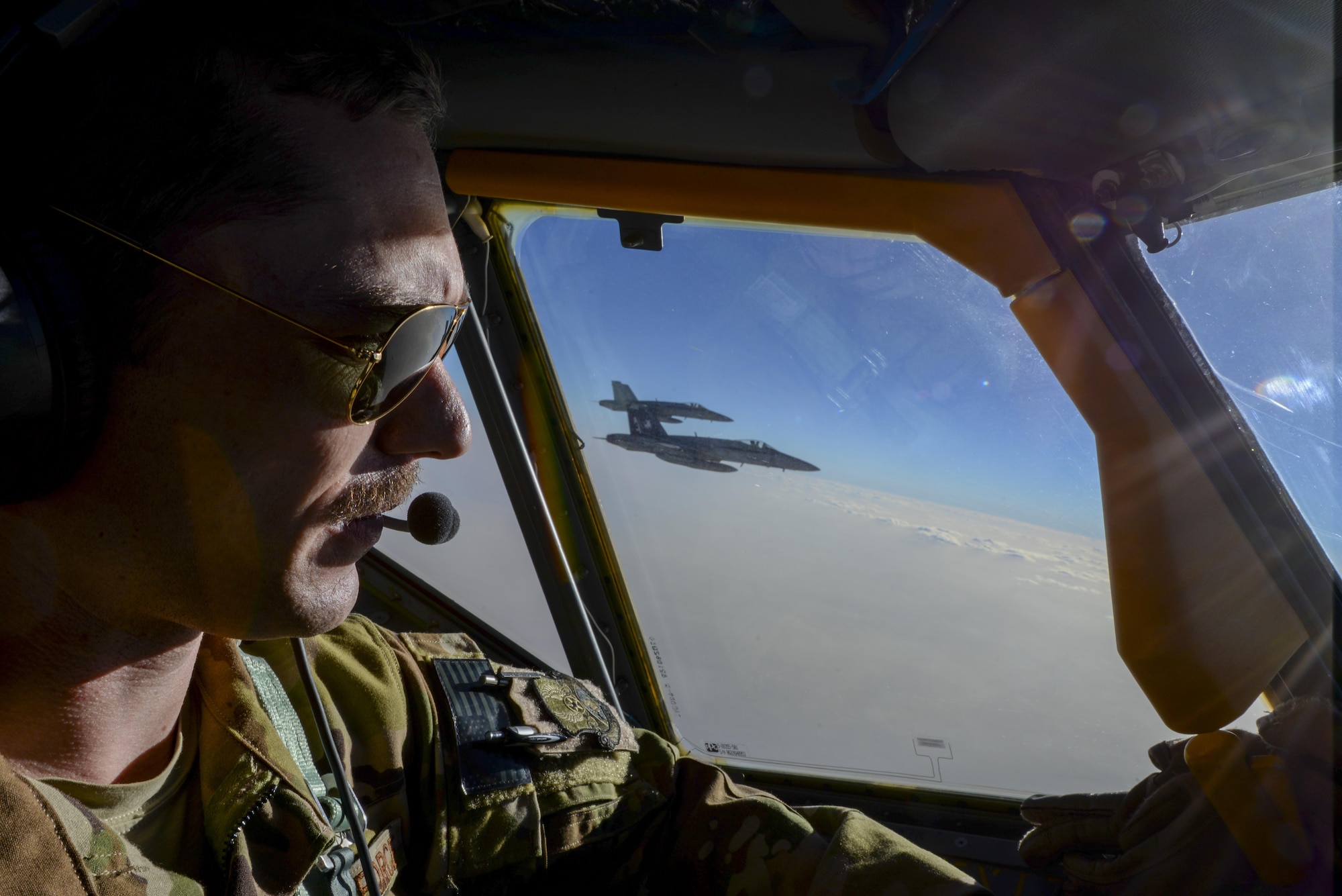 U.S. Air Force Capt. Timothy Black, aircraft commander, pilots a KC-135 Stratotanker on a combat refueling mission over Southwest Asia while two U.S. Navy F/A-18Cs from the VFA-37 Ragin' Bulls fly in formation alongside the aircraft May 21, 2017. Assigned to the 340th Expeditionary Air Refueling Squadron, out of Al Udeid Air Base, Qatar, the tanker from the 186th Air Refueling Wing, Mississippi Air National Guard was fitted with a drogue attached to the boom, for specialized receiver equipment on Navy and coalition aircraft. The 340 EARS maintains a 24/7 presence in the AOR, supporting Operation Inherent Resolve and the fight against ISIS. (U.S. Air National Guard photo by Master Sgt. Andrew J. Moseley/Released)
