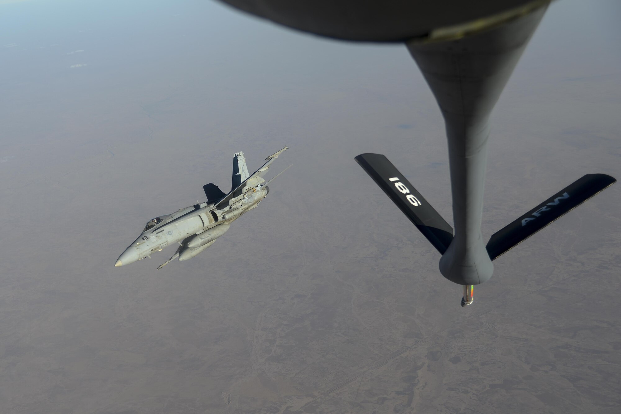 A U.S. Navy F/A-18C from the VFA-37 Ragin' Bulls breaks right after receiving fuel from a U.S. Air Force KC-135 Stratotanker over Southwest Asia May 21, 2017.  Assigned to the 340th Expeditionary Air Refueling Squadron, out of Al Udeid Air Base, Qatar, the tanker from the 186th Air Refueling Wing, Mississippi Air National Guard was fitted with a drogue attached to the boom, for specialized receiver equipment on Navy and coalition aircraft. The 340th EARS maintains a 24/7 presence in the AOR, extending the missions of aircraft supporting Operation Inherent Resolve and the fight against ISIS. (U.S. Air National Guard photo by Master Sgt. Andrew J. Moseley/Released)