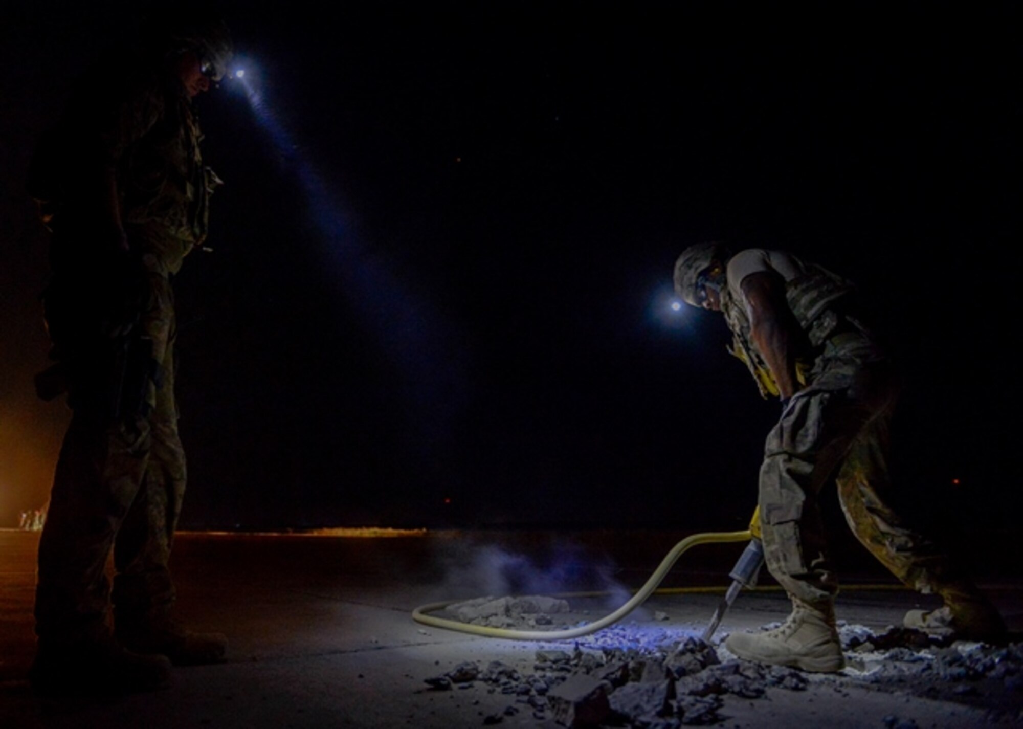Two members of the 1st Expeditionary Civil Engineer Group repair the flightline at Qayyarah West Airfield during a restoration project May 16, 2017. Qayyarah West is an airfield in northern Iraq’s Ninawa Province and serves as the logistical hub and strategic launching pad resupplying the frontlines in an attempt to recapture Mosul. (U.S. Air Force photo by Staff Sgt. Michael Battles)