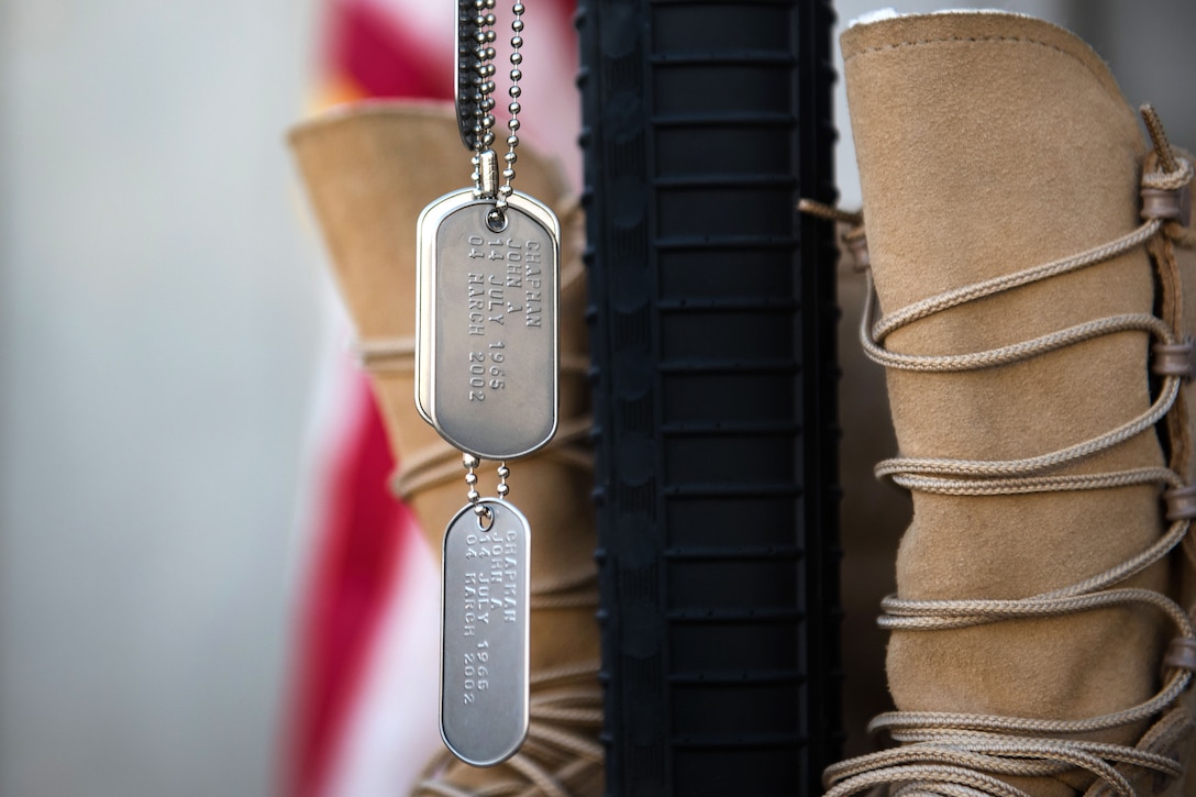 Dog tags displaying the names of Air Force airmen killed in action, hang from a rifle during a Memorial Day ceremony at Bagram Airfield, Afghanistan, May 29, 2017. The boots, rifle and helmet make what is called the Battlefield Cross, which is a symbolic replacement of a cross and is used to honor and show respect to deceased service members. Air Force photo by Staff Sgt. Benjamin Gonsier