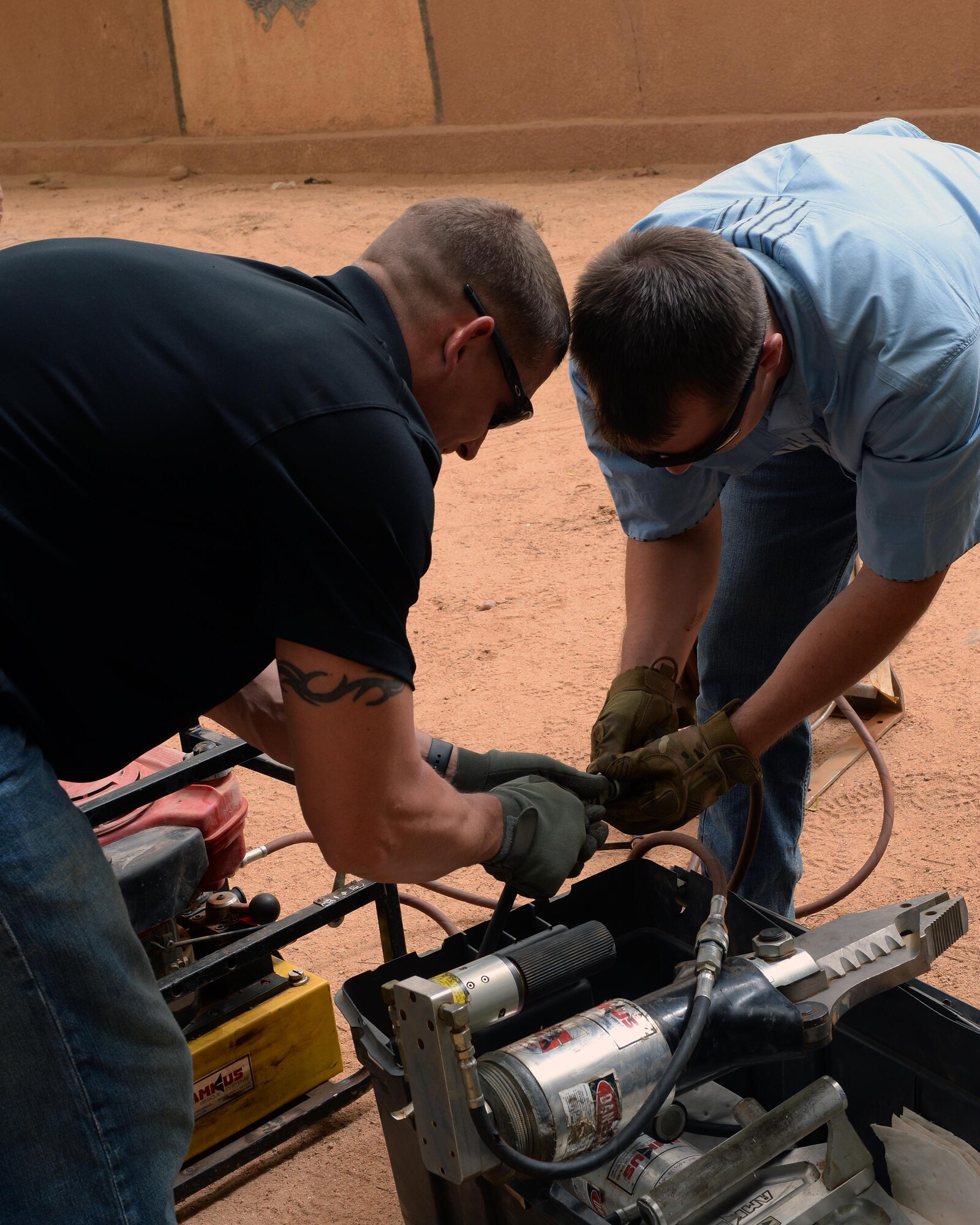 Master Sgt. Gerald Allen, left, 724th Expeditionary Air Base Squadron Fire Department assistant chief of operations, and Senior Airmen Jayden Steier, 724th EABS Fire Department driver operator, connect a combination spreader tool to a motor driven hydraulic pump in Agadez, Niger, May 16, 2017. The combination spreader tool is a hydraulic rescue tool, commonly referred to as the Jaws of Life, firefighters use to extricate a person trapped in an emergency situation. (U.S. Air Force photo by Senior Airman Jimmie D. Pike)