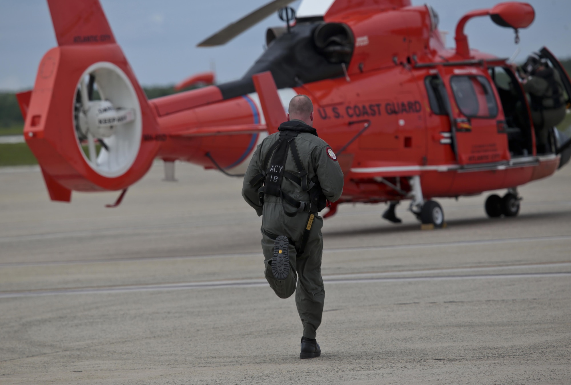 A U.S. Coast Guard HH-65C Dolphin crew member from Coast Guard Air Station Atlantic City runs to his helicopter after an alert during a three-day Aeropsace Control Alert CrossTell live-fly training exercise at Atlantic City International Airport, N.J., May 24, 2017. Representatives from the Air National Guard fighter wings, Civil Air Patrol, and U.S. Coast Guard rotary-wing air intercept units will conduct daily sorties from May 23-25 to hone their skills with tactical-level air-intercept procedures. (U.S. Air National Guard photo by Master Sgt. Matt Hecht/Released)