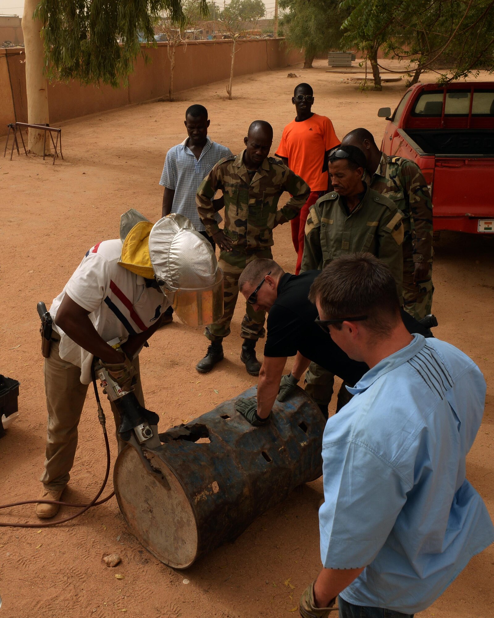 Members of the Forces Armées Nigeriennes watch as Senior Airman Micah Moody, 724th Expeditionary Air Base Squadron Fire Department driver operator, cuts through metal with a combination spreader tool in Agadez, Niger, May 16, 2017. The combination spreader tool is a hydraulic rescue tool, commonly referred to as the Jaws of Life, firefighters use to extricate a person trapped in an emergency situation. (U.S. Air Force photo by Senior Airman Jimmie D. Pike)