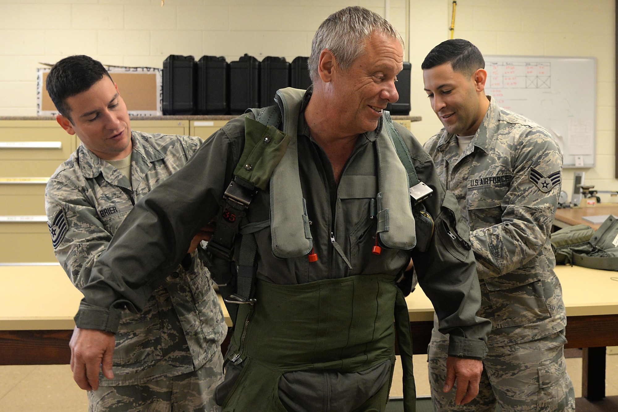 Air Force Tech. Sgt. Kyle P. Brier and Air Force Senior Airman Matthew Cruz, 177th Fighter Wing Air Crew Flight Equipment, New Jersey Air National Guard, help NBC reporter Brian Thompson, don his survival gear on May 24, 2017, in Atlantic City, N.J. Thompson flew in an F-16D Fighting Falcon during a CrossTell familiarization flight to help increase media and public awareness on Aerospace Control Alert. (U.S. Air National Guard photo by Airman 1st Class Cristina J. Allen/Released)