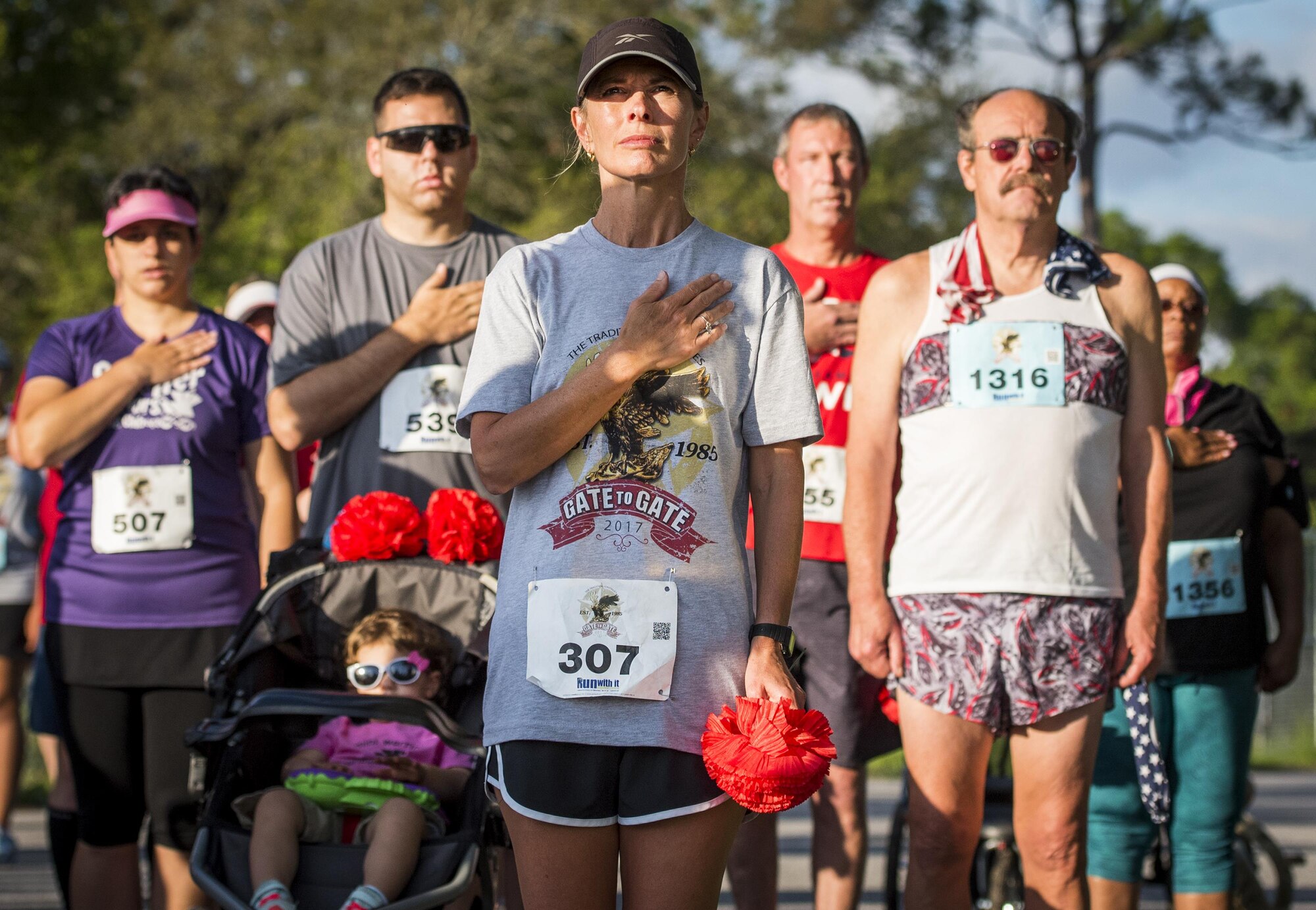 Jennifer Azzano holds her hand over her heart during the playing of the National Anthem prior to the 32nd annual Gate to Gate run at Eglin Air Force Base, Fla., May 27.  Azzano is the spouse of Brig. Gen. Christopher Azzano, the 96th Test Wing commander. More than 900 people participated at this year’s event.  (U.S. Air Force photo/Samuel King Jr.)