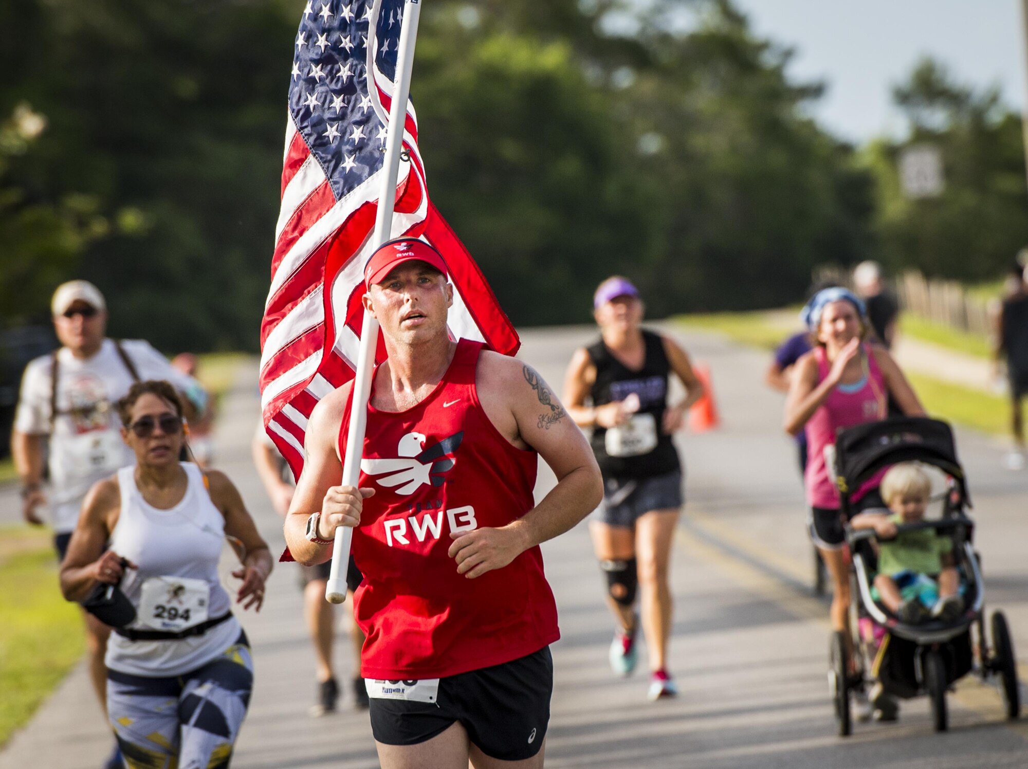 Chris Morelli carries an American flag as he runs toward the finish line of the 32nd annual Gate to Gate run at Eglin Air Force Base, Fla., May 27.  More than 900 people participated at this year’s event.  (U.S. Air Force photo/Samuel King Jr.)