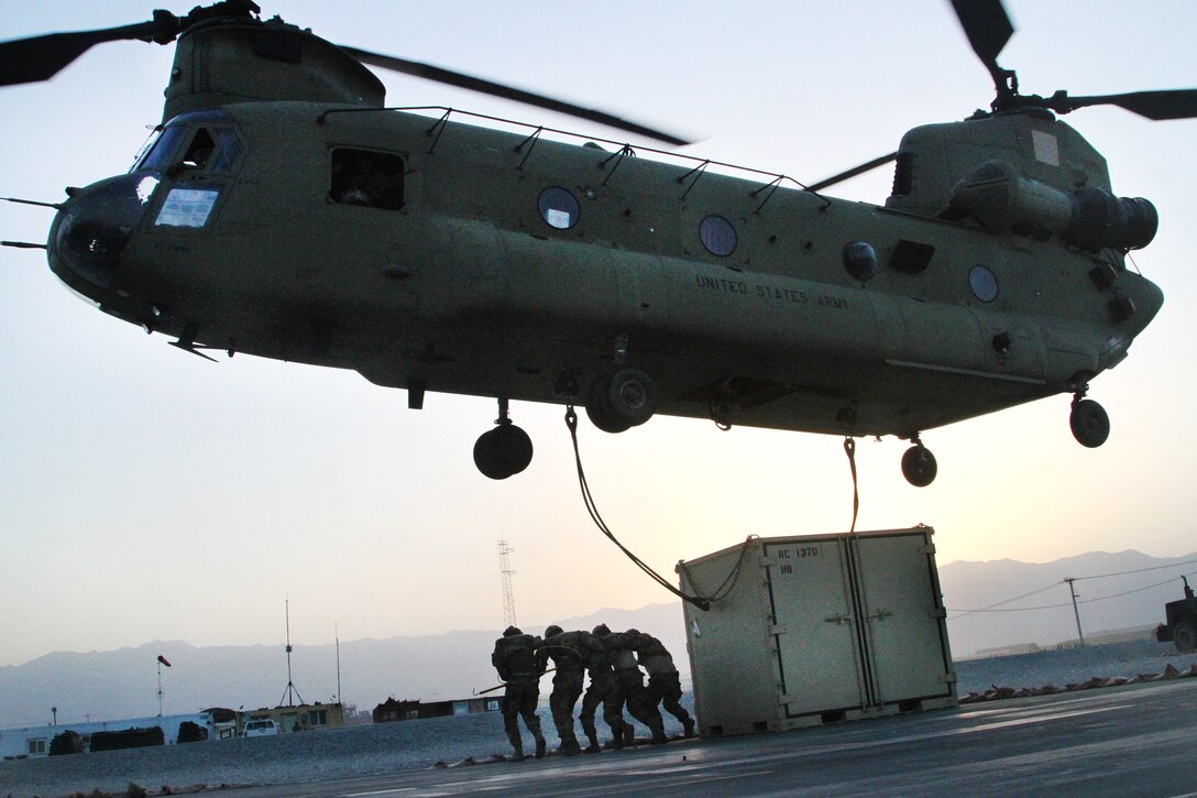 Soldiers hurry away as a team after hooking up a container to a CH-47 Chinook helicopter during slingload operations at Bagram Airfield, Afghanistan, May 22, 2017. Army photo by Sgt. 1st Class Shelia Cooper