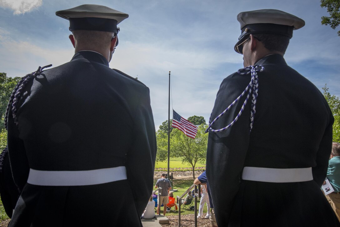 The American flag can be seen flying at half-staff between two Clemson University Army Reserve Officers’ Training Corps cadets during a Memorial Day observance in Clemson’s Memorial Park, May 28, 2017. (U.S. Army Reserve photo by Staff Sgt. Ken Scar)