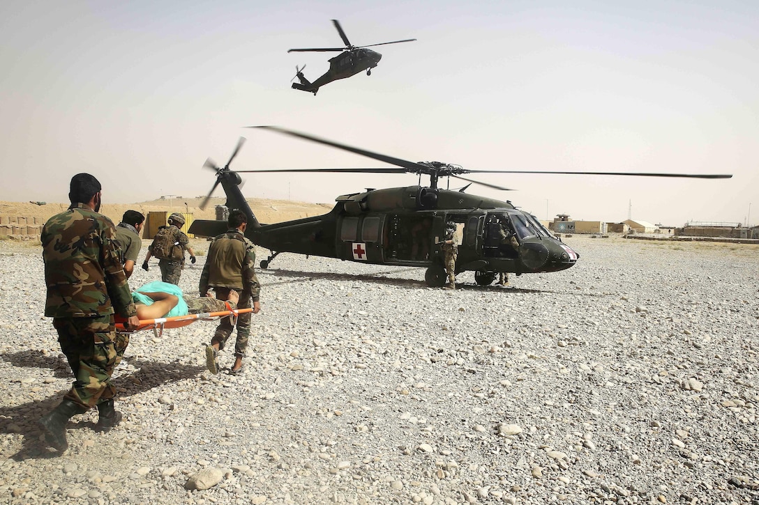 A U.S. sailor, front left, leads Afghan soldiers carrying a wounded Afghan soldier to be evacuated on a UH-60 Black Hawk medevac helicopter at Camp Nolay, Afghanistan, May 23, 2017. Marine Corps photo by Sgt. Lucas Hopkins