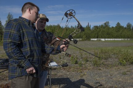 U.S. Air Force Staff Sgt. Sean McCarty, 673d Medical Group radiology technician, teaches Senior Airman Jacub Dabrowsk, 673s MDG radiology technician, how to use a compound bow during a Safety Day event at Hillberg stables at Joint Base Elmendorf-Richardson, Alaska, May 25, 2017. Safety Day event activities highlighted all-terrain vehicle, kayaking, hiking, mountain biking, archery, rock climbing and fly fishing safety. 
