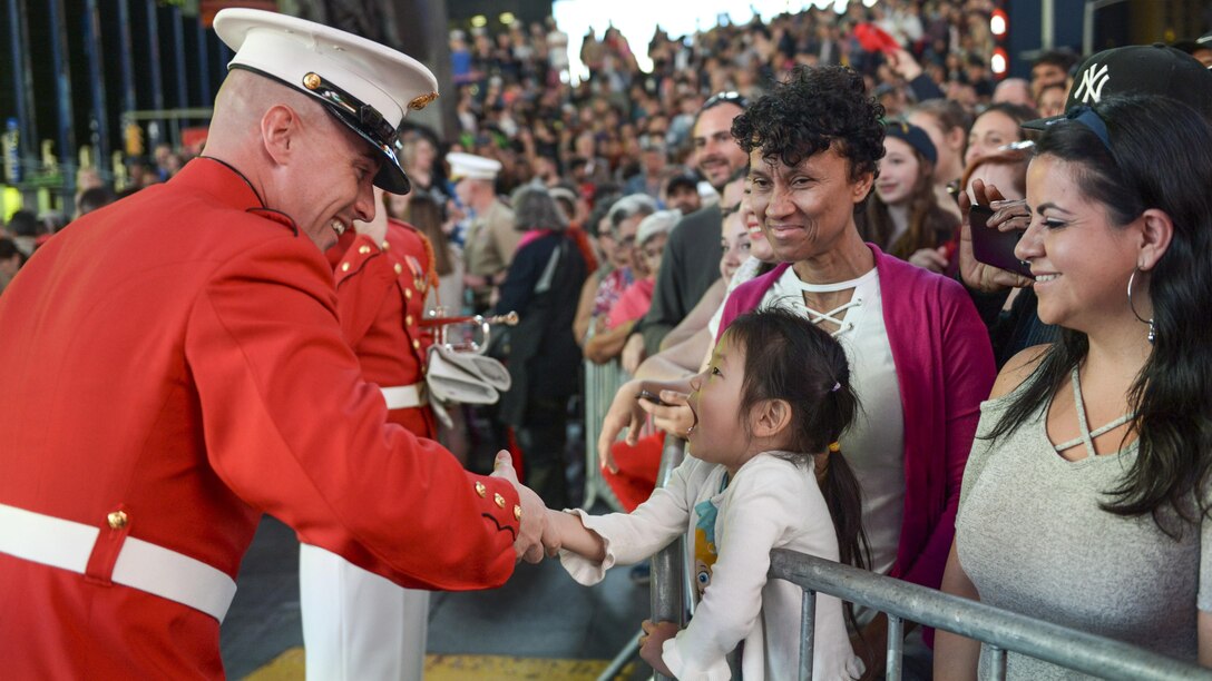 A Marine Drum and Bugle Corps member greets a young fan after performing in Times Square in New York City as part of Fleet Week New York, May 27, 2017. Sailors, Marines and Coast Guardsmen demonstrate capabilities and teach the people of New York about America's sea services during the yearly observance. Marine Corps photo by Lance Cpl. Samantha Bray