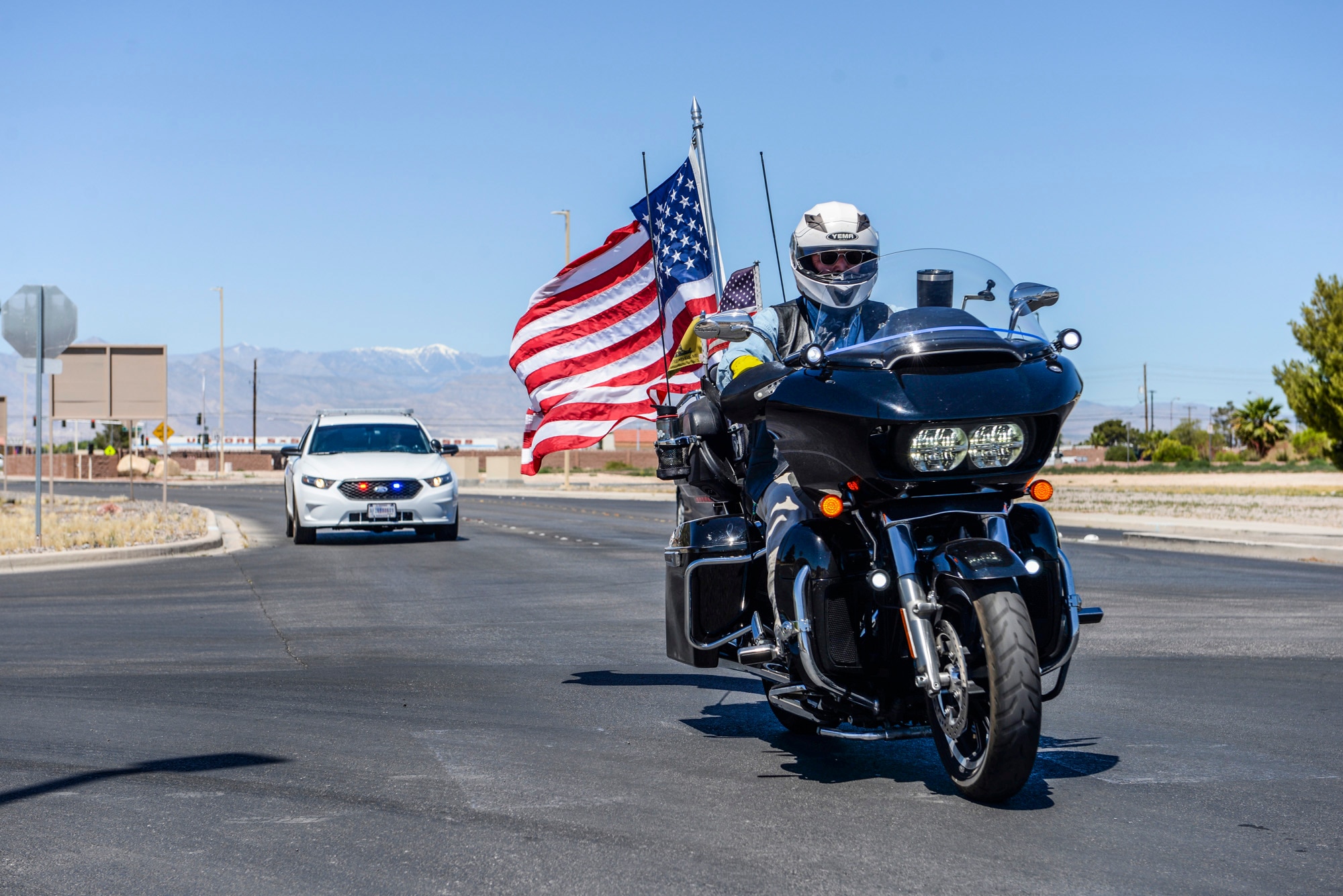 A biker rides his motorcycle while flying the American Flag at Nellis Air Force Base, Nev., May 21, 2017. More than 70 bikers rode together and made a pit stop at Nellis AFB before finishing their ride at Craig Ranch Park for the American Patriot Festival. (U.S. Air Force photo by Airman 1st Class Andrew D. Sarver/Released)