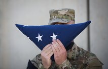 Senior Master Sgt. Michael Miller, 455th Expeditionary Communications Squadron, holds the American flag up to his face during a Memorial Day ceremony at Bagram Airfield, Afghanistan, May 29, 2017. Memorial Day, observed on the last Monday of May, serves as a day for remembering service members who have died while serving. (U.S. Air Force photo by Staff Sgt. Benjamin Gonsier)