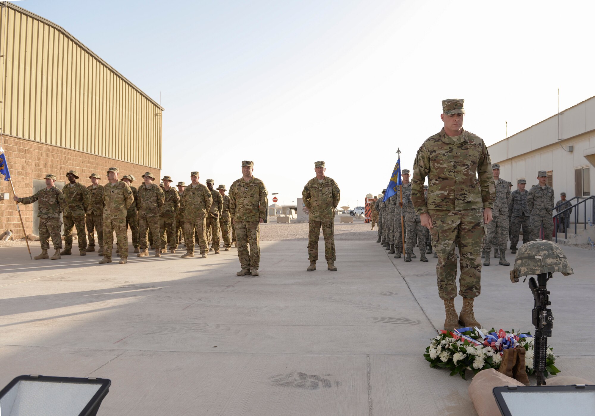 U.S. Air Force Brig. Gen. Darren V. James, commander of the 379th Air Expeditionary Wing, stands at attention after laying a wreath at the foot of the fallen soldier memorial as military members stand in formation behind him at Al Udeid Air Base, Qatar, May 29, 2017. The formation was part of a Memorial Day Retreat Ceremony held in honor of those who have died while in military service. (U.S. Air Force photo by Tech. Sgt. Bradly A. Schneider/Released)