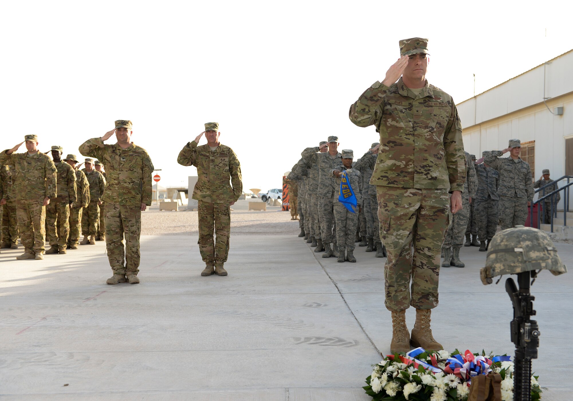 U.S. Air Force Brig. Gen. Darren V. James, commander of the 379th Air Expeditionary Wing, salutes after laying a wreath at the foot of the fallen soldier memorial as military members stand in salute behind him at Al Udeid Air Base, Qatar, May 29, 2017. The formation was part of a Memorial Day Retreat Ceremony held in honor of those who have died while in military service. (U.S. Air Force photo by Tech. Sgt. Bradly A. Schneider/Released)
