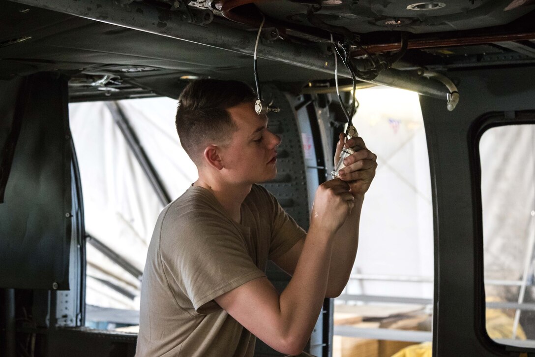 A soldier disassembles interior cables and wiring during maintenance on an HH-60 Black Hawk helicopter at Bagram Airfield, Afghanistan, May 25, 2017. Army photo by Capt. Brian Harris 