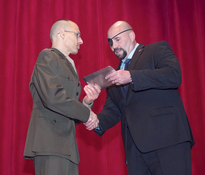 U.S. Marine Corps Brig. Gen. Thomas A. Gorry, left, president, Marine Corps University, presents a gift to retired Marine Gunnery Sgt. Nick A. Popaditch, supervisor at Tesla Motors, in honor of him giving the lecture at the 17th Annual Sgt. Walter K. Singleton distinguished lecture series held at Warner Hall at Marine Corps University.