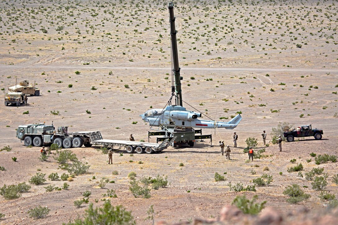 Marines use heavy equipment to lift a helicopter while participating in a live-fire and aircraft recovery mission during training at Marine Corps Air Ground Combat Center Twentynine Palms, Calif., May 24, 2017. Marine Corps photo by Lance Cpl. Becky L. Calhoun